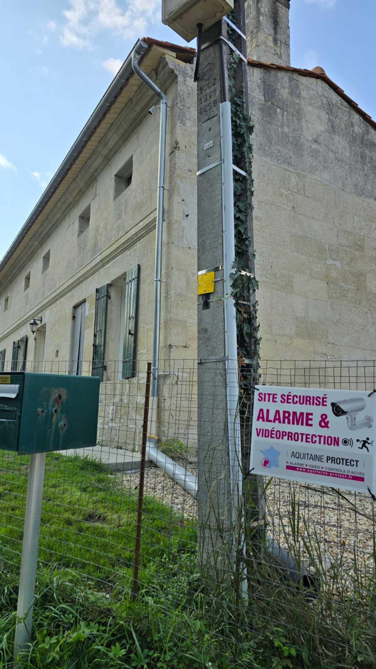 Technicien installant une caméra de sécurité dôme au plafond tout en gérant le système de maison intelligente avec un smartphone affichant un code de verrouillage.